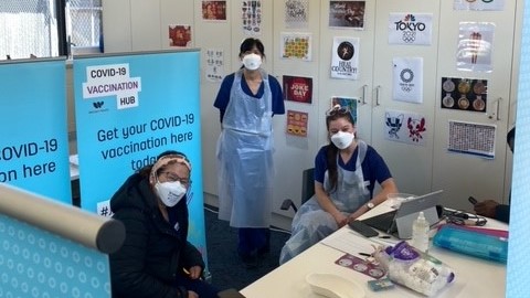 Two nurses and resident wearing face mask pose for a photo at a walk-in vaccination clinic