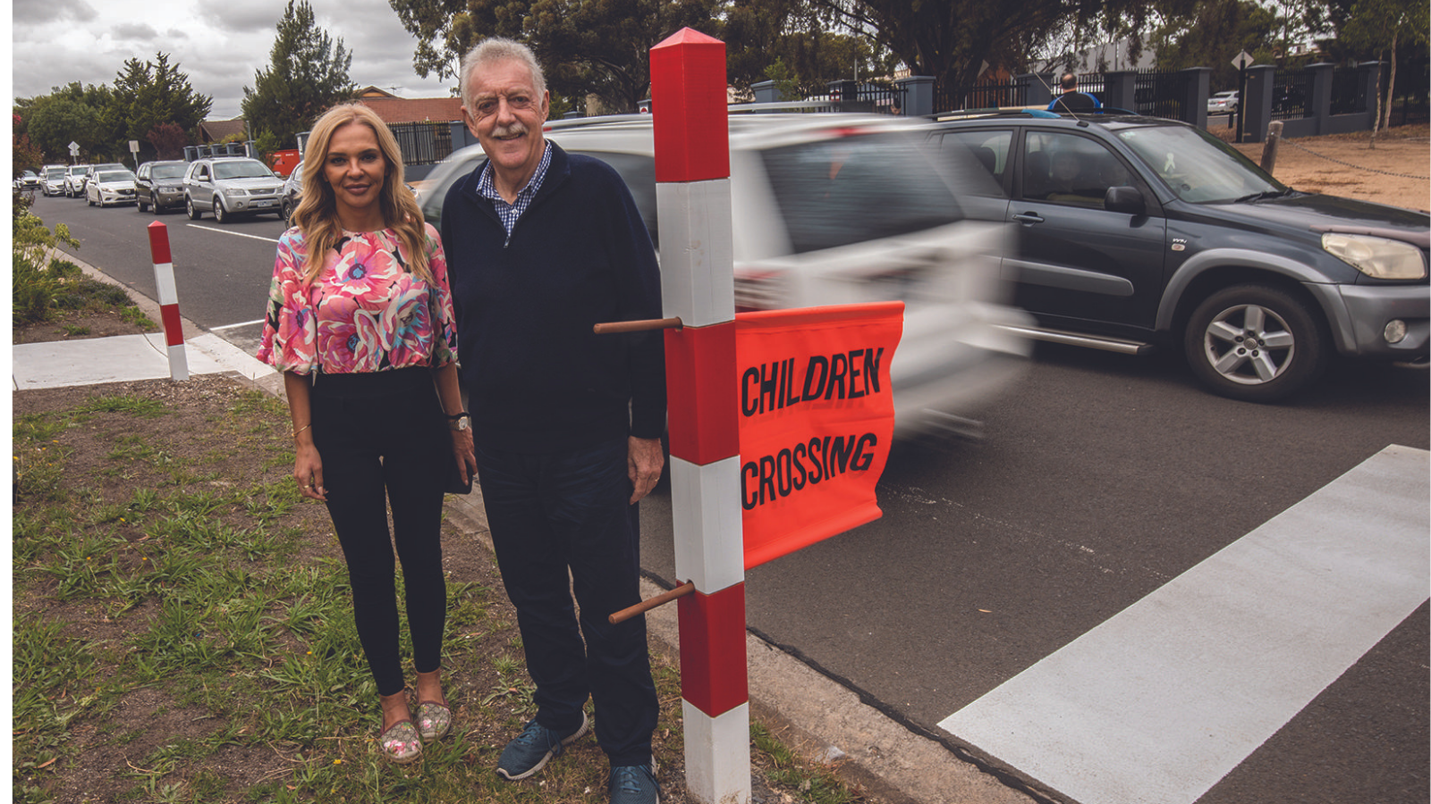 Two people standing in front of a school crossing