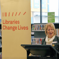 Cr Borg speaking at lecturn with shelves of books behind her and a large banner with the words "Libraries change lives"