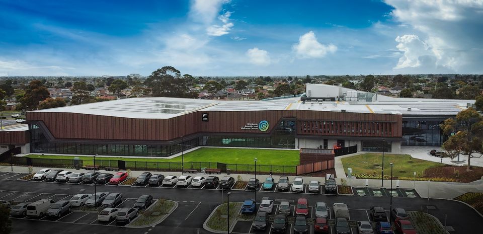 The image shows the Brimbank Aquatic and Wellness Centre with the carpark in the foreground.