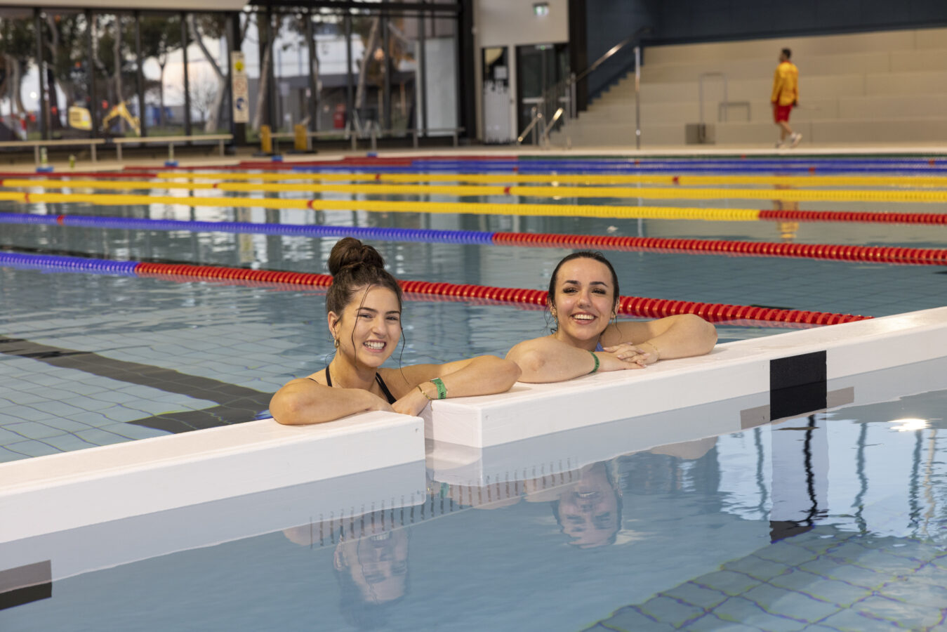 Images shows two swimmers smiling at you in the Brimbank Aquatic and Wellness Centre indoor pool